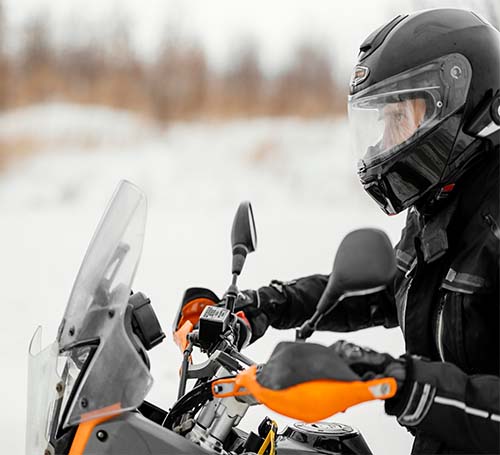 Rider on his motorcycle with snow in the background.

